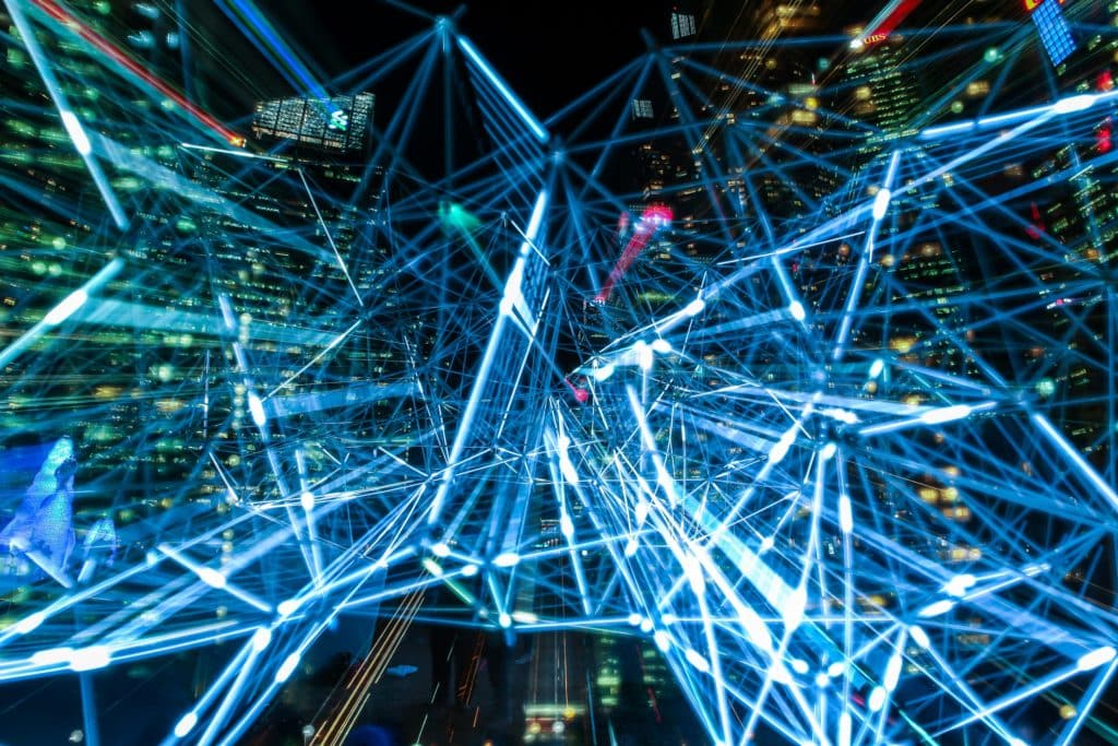 An image of interconnecting beams of light superimposed over a city a night meant to symbolize the connections of devices in industry 4.0.