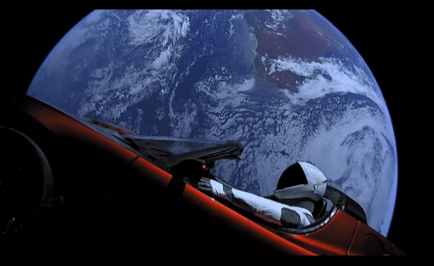 a still of the starman mannequin and tesla roadster with earth in the background from the SpaceX.com live feed..