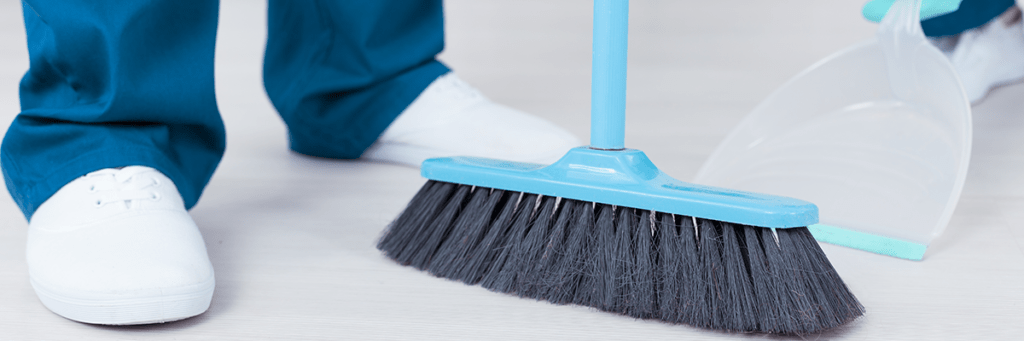 an image of a cleaning crew sweeping into a dust pan.