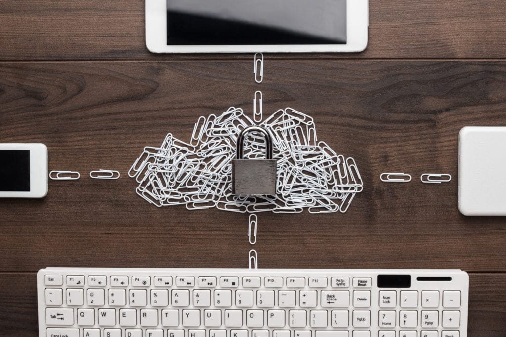 A picture of digital devices on a table connected through a chain of paper clips.